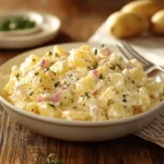 A creamy homemade potato salad made with Hellmann's mayonnaise, garnished with fresh herbs in a serving bowl.